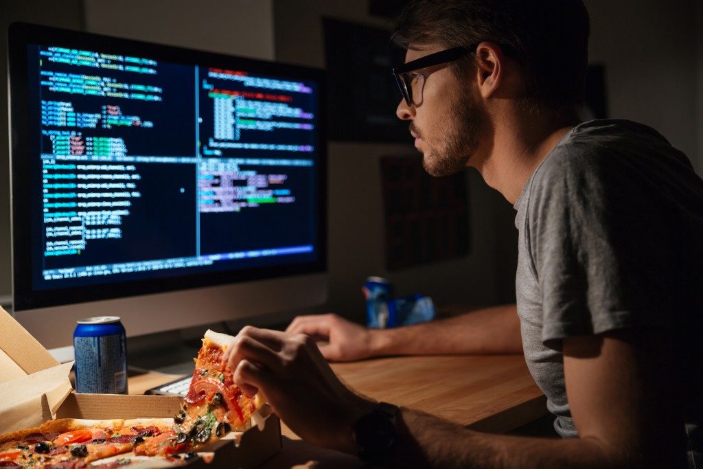 man coding while eating pizza