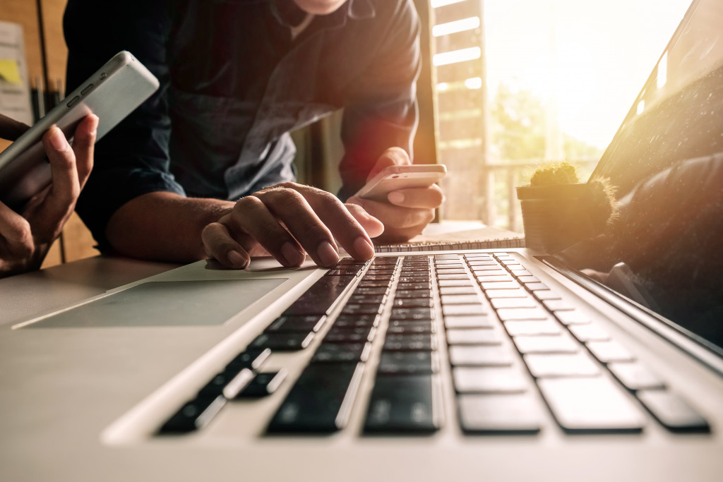 men typing on laptop holding cellphones