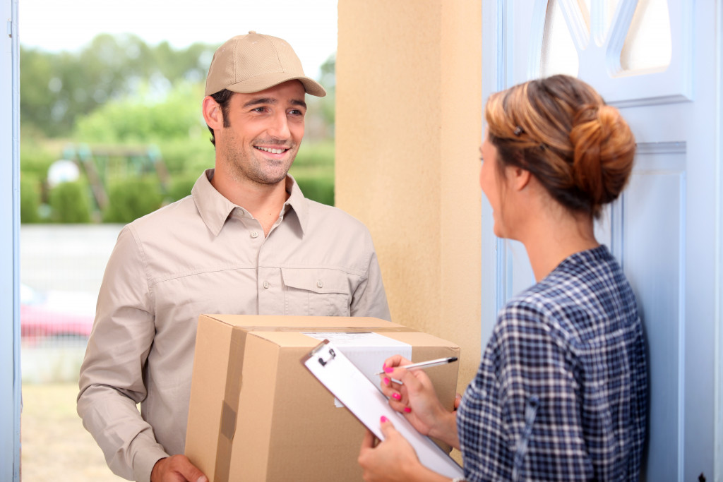 a deliverry man at the door handing a parcel to a client