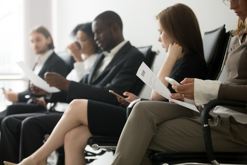 people wearing formal attire and holding resumes while sitting in line waiting 