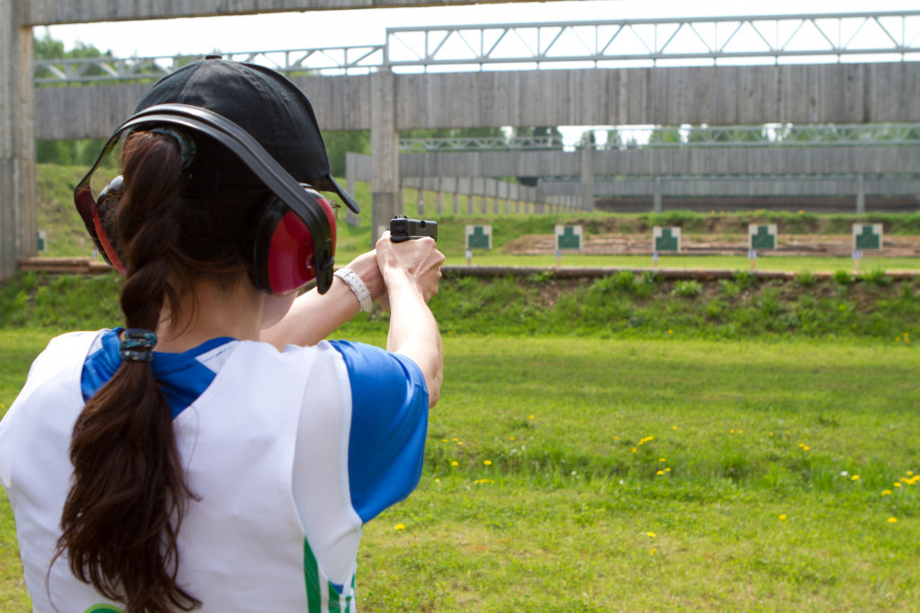 woman shooting in shooting range in open grass field