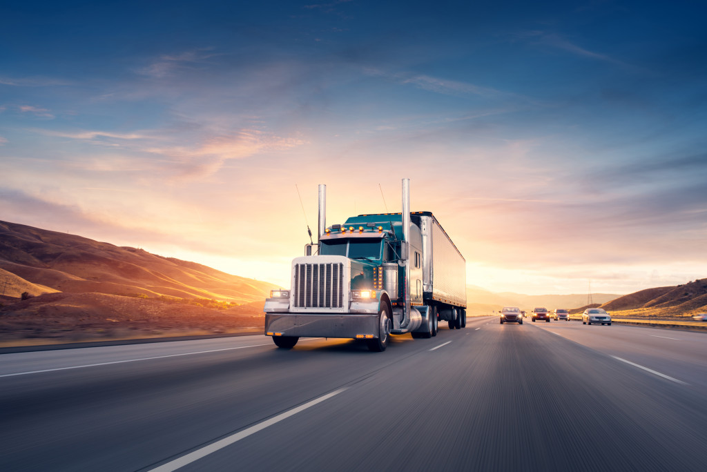 Semi truck on a highway with cars behind it.