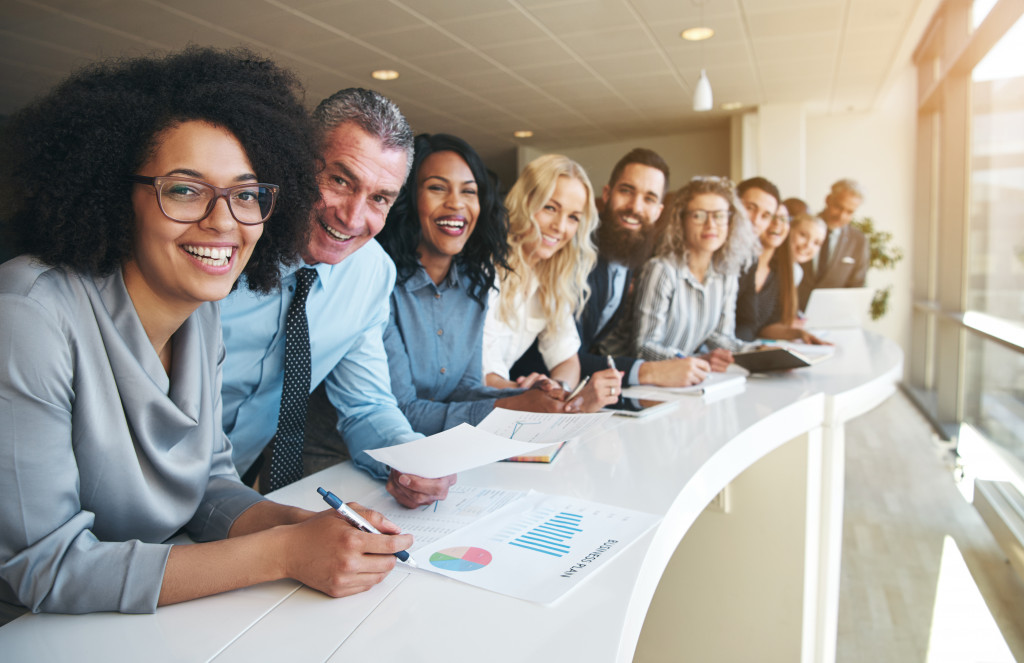 diverse set of employees happily smiling in a long table near the window